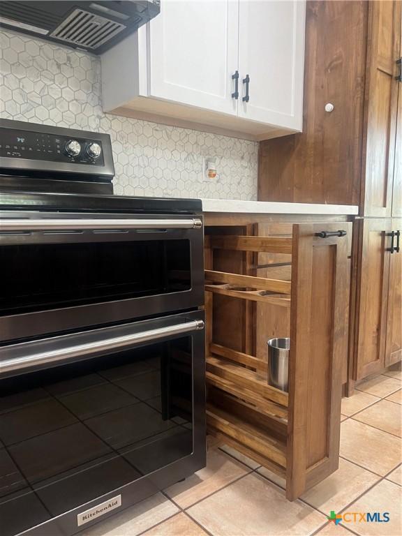1102 Crockett, Cotulla, TX 78014 - kitchen view of double oven range, exhaust hood, white cabinets, and tasteful backsplash