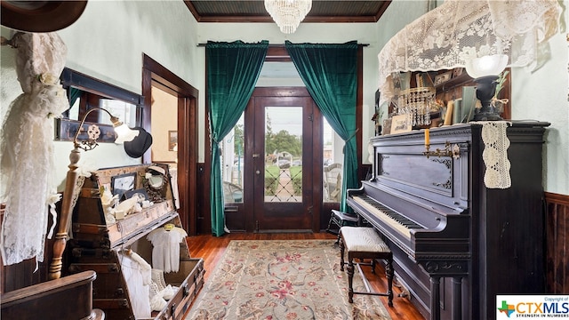 foyer with hardwood / wood-style flooring, crown molding, and a notable chandelier