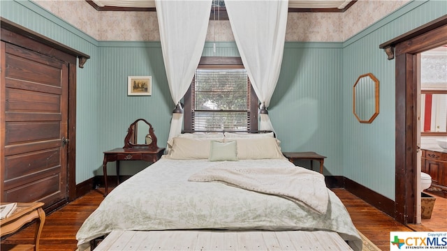 bedroom with dark hardwood / wood-style floors, ensuite bath, and crown molding