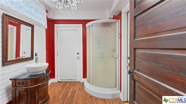 bathroom featuring ornamental molding, walk in shower, vanity, hardwood / wood-style floors, and a chandelier