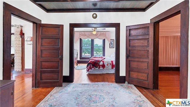 hall with wood walls, light hardwood / wood-style floors, and wood ceiling