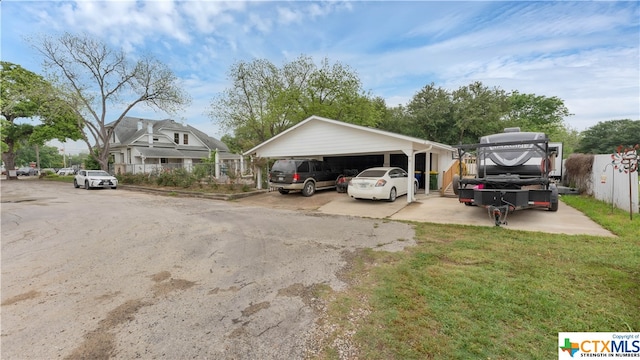 view of parking / parking lot featuring a yard and a carport