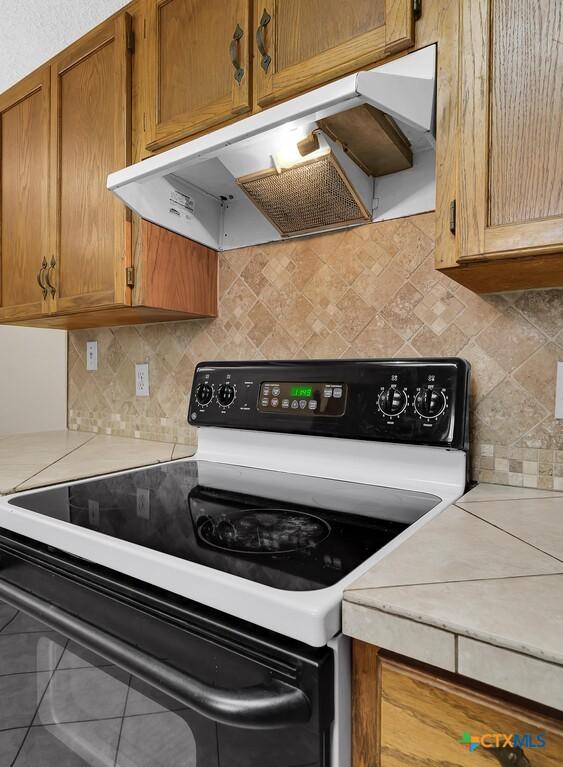 1117 Lindsey Cir, Belton, TX 76513 - kitchen featuring under cabinet range hood, light countertops, brown cabinetry, and electric range