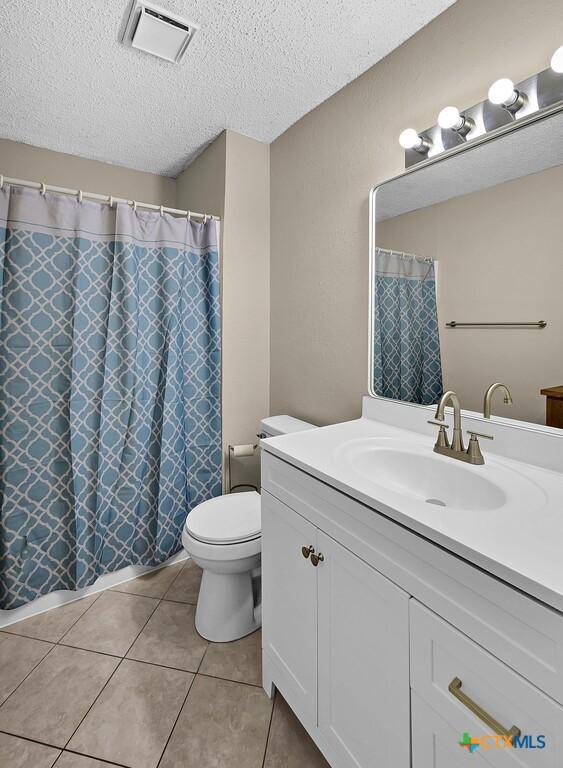 1117 Lindsey Cir, Belton, TX 76513 - bathroom featuring vanity, toilet, a textured ceiling, tile patterned floors, and visible vents