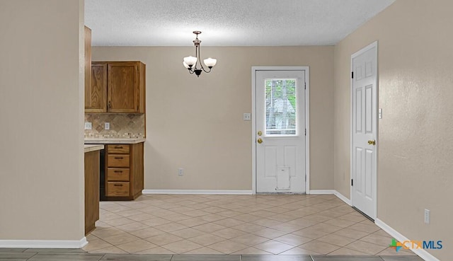 1117 Lindsey Cir, Belton, TX 76513 - interior space with light countertops, backsplash, a chandelier, a textured ceiling, and brown cabinetry