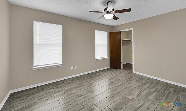 1117 Lindsey Cir, Belton, TX 76513 - unfurnished bedroom featuring baseboards, multiple windows, a walk in closet, and a textured ceiling