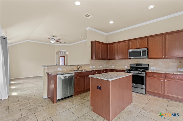 kitchen with stainless steel appliances, sink, kitchen peninsula, light stone countertops, and a kitchen island