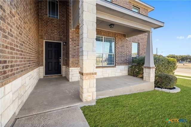 property entrance featuring covered porch and a lawn