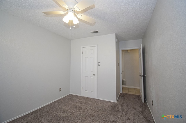 unfurnished bedroom featuring ceiling fan, a closet, a textured ceiling, and carpet flooring