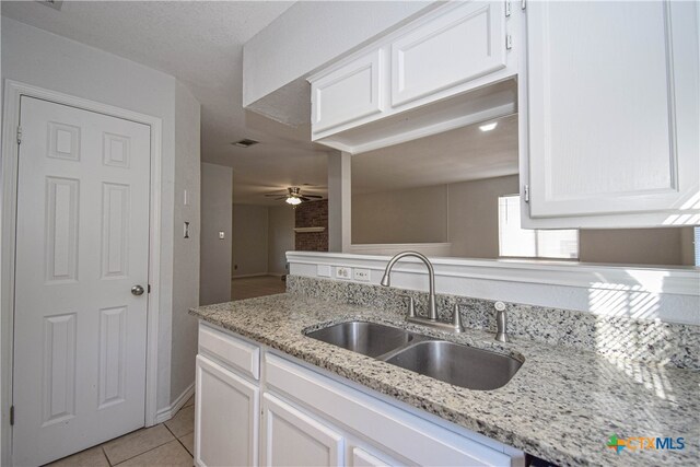 kitchen featuring white cabinets, light stone countertops, ceiling fan, sink, and light tile patterned flooring