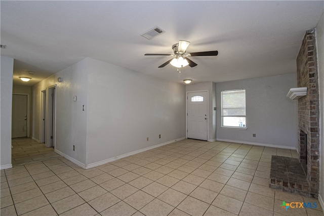 tiled entrance foyer featuring a brick fireplace and ceiling fan