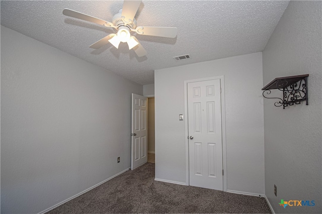 unfurnished bedroom with ceiling fan, a textured ceiling, and dark colored carpet