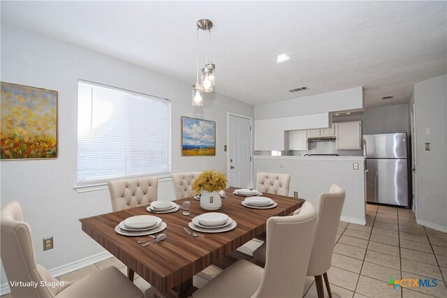 kitchen with light tile patterned floors, stainless steel refrigerator, pendant lighting, and kitchen peninsula