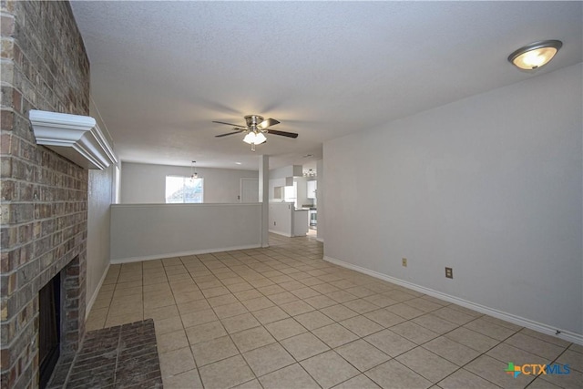 interior space featuring a brick fireplace, a textured ceiling, ceiling fan, and light tile patterned floors