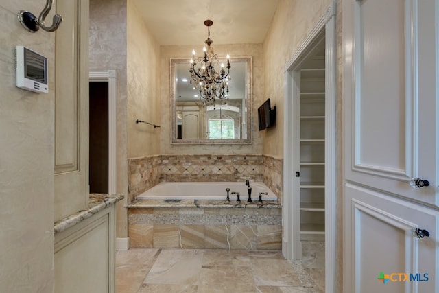 bathroom featuring a notable chandelier and tiled tub