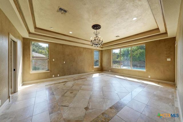 spare room with ornamental molding, a wealth of natural light, a notable chandelier, and a tray ceiling