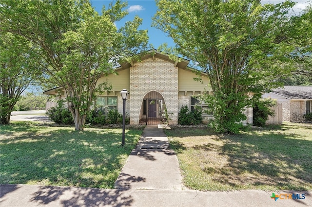 view of front of house with a front lawn, fence, and brick siding