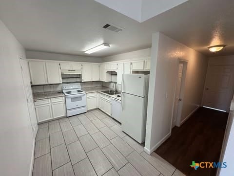 kitchen featuring decorative backsplash, sink, white cabinets, and white appliances