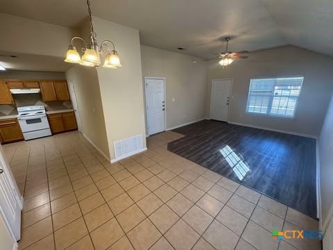 kitchen with white range, pendant lighting, vaulted ceiling, light hardwood / wood-style floors, and ceiling fan with notable chandelier