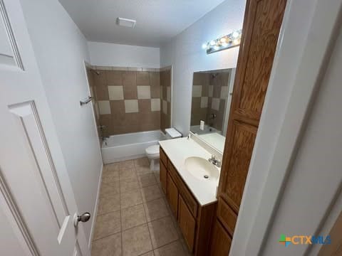 full bathroom featuring tile patterned flooring, vanity, toilet, and tiled shower / bath