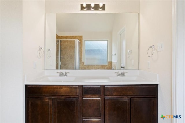 bathroom with a sink, a stall shower, and double vanity