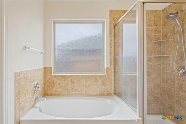 full bathroom featuring plenty of natural light, a shower stall, and a bath