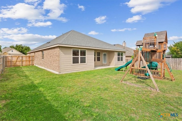 back of house featuring a playground, a yard, a fenced backyard, and brick siding