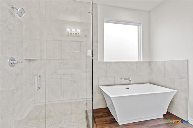 812 Waylon Cir, Killeen, TX 76542 - bathroom featuring a shower stall, a soaking tub, wood finished floors, and tile walls