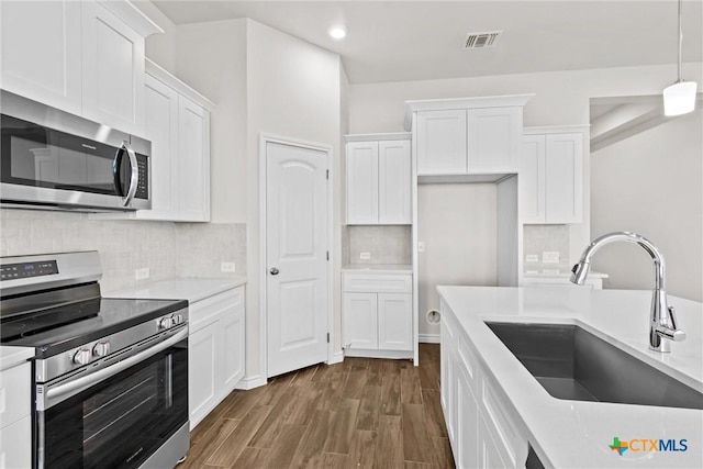 812 Waylon Cir, Killeen, TX 76542 - kitchen with appliances with stainless steel finishes, white cabinetry, light countertops, dark wood-type flooring, and recessed lighting