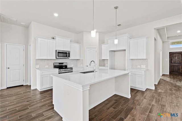812 Waylon Cir, Killeen, TX 76542 - kitchen with appliances with stainless steel finishes, dark wood-type flooring, tasteful backsplash, white cabinetry, and a center island with sink