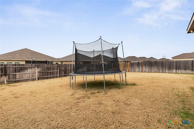 view of yard featuring a trampoline and a fenced backyard