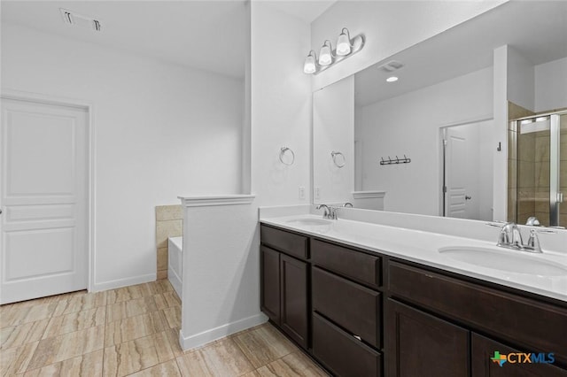 bathroom featuring double vanity, visible vents, a stall shower, and a sink