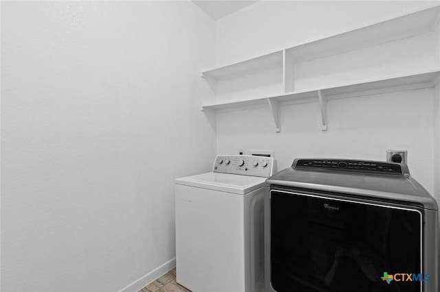 laundry area with laundry area, washing machine and dryer, and baseboards