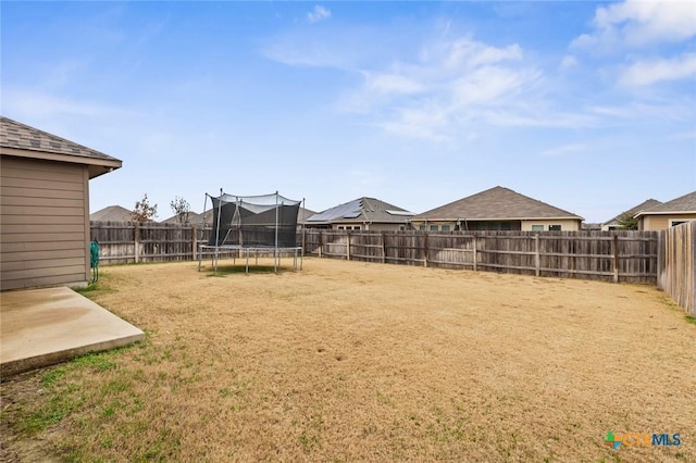 view of yard featuring a fenced backyard, a patio area, and a trampoline