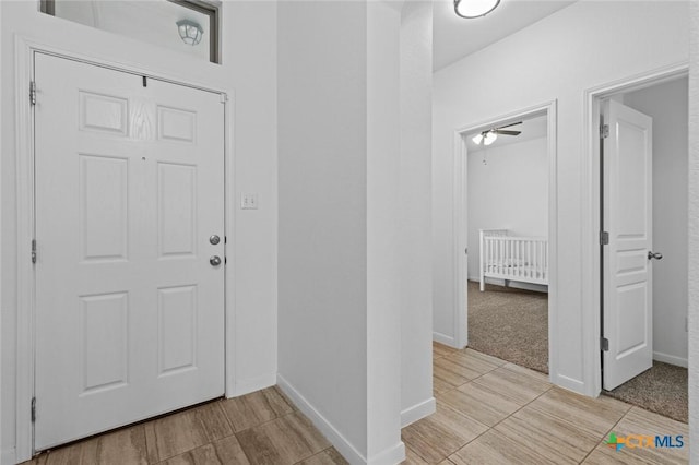 foyer entrance with baseboards and ceiling fan