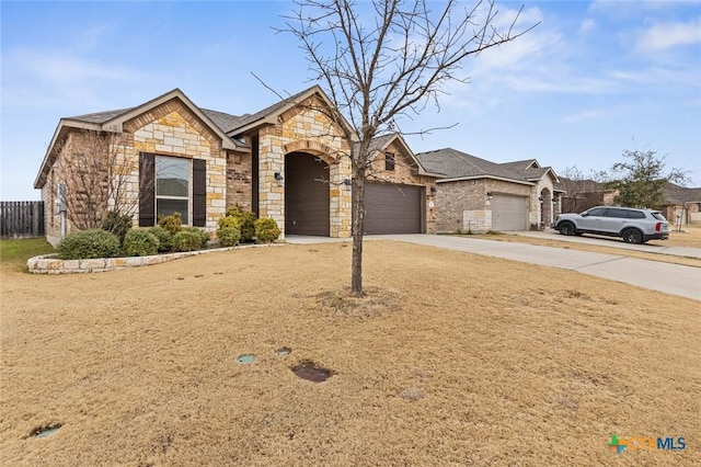 view of front of home with a garage, fence, stone siding, and driveway