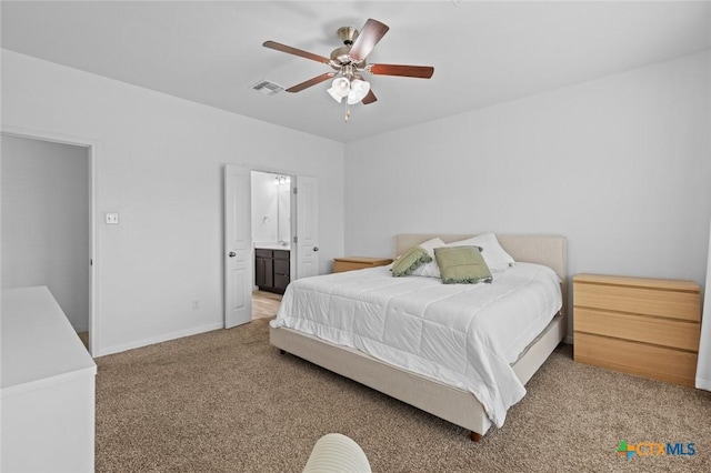 carpeted bedroom with visible vents, ceiling fan, ensuite bathroom, and baseboards