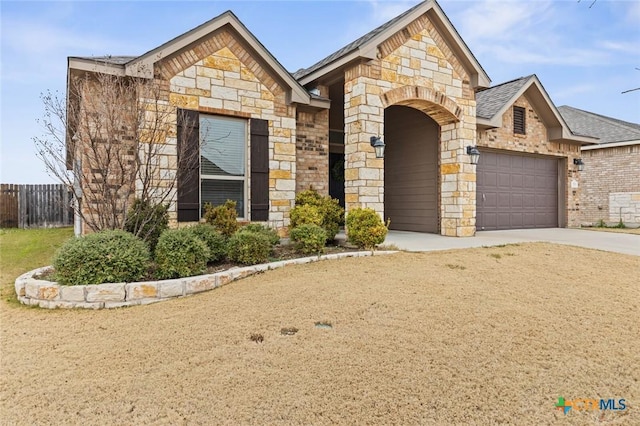 view of front of house with concrete driveway, a garage, fence, and stone siding