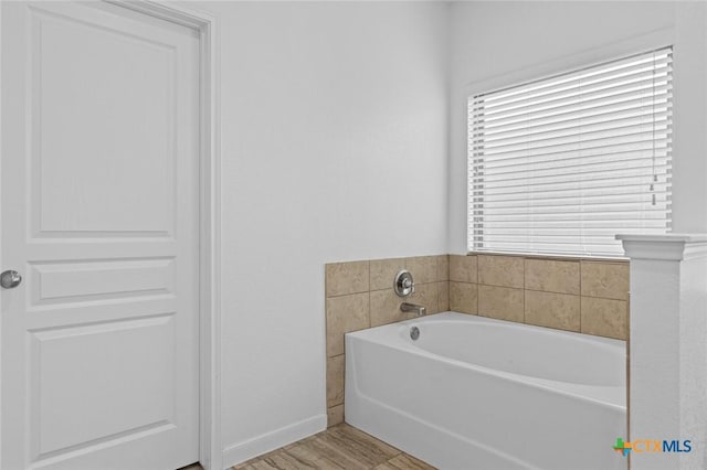 full bathroom with baseboards, a garden tub, and wood finished floors