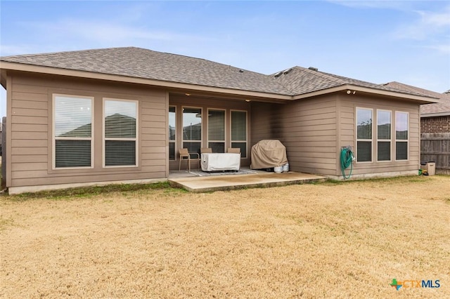 back of house featuring a lawn, roof with shingles, a patio, and fence