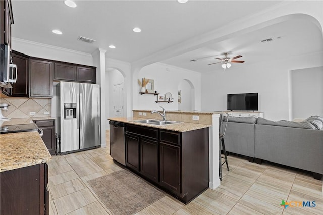 kitchen featuring a ceiling fan, arched walkways, a sink, stainless steel appliances, and open floor plan