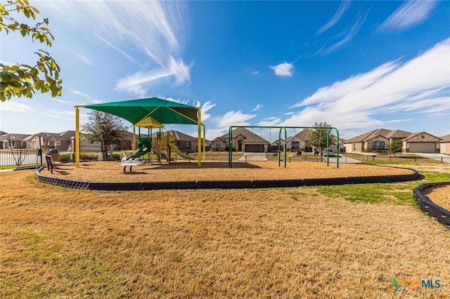 community play area with fence, a lawn, and a residential view