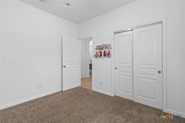 unfurnished bedroom featuring a closet, baseboards, and carpet