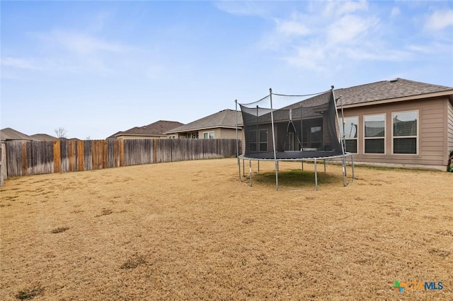 view of yard featuring a trampoline and a fenced backyard