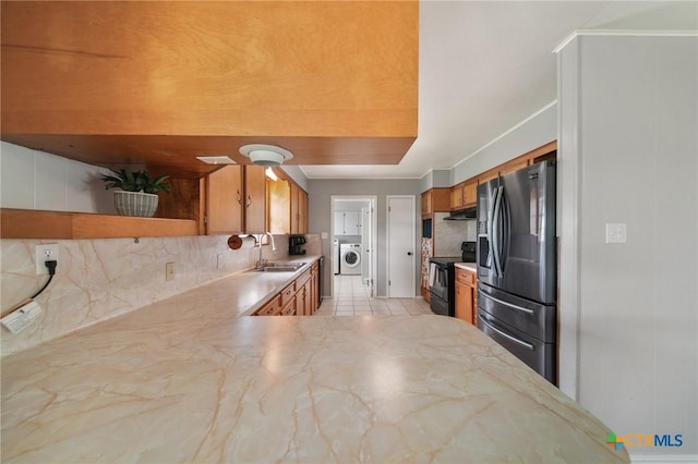 kitchen with brown cabinetry, electric range, stainless steel fridge with ice dispenser, a sink, and backsplash