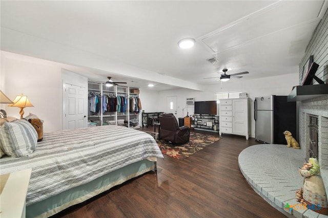 bedroom featuring attic access, visible vents, a brick fireplace, wood finished floors, and freestanding refrigerator