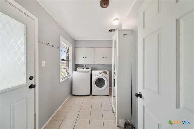 washroom with cabinet space, light tile patterned floors, baseboards, and washer and clothes dryer