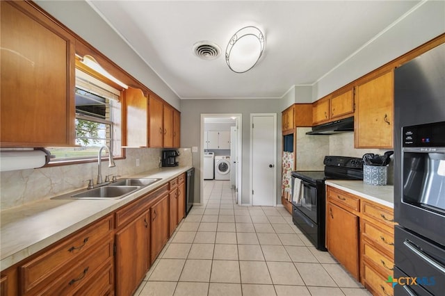 kitchen with brown cabinetry, independent washer and dryer, visible vents, a sink, and black appliances