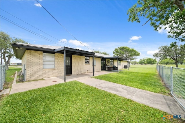 rear view of property with brick siding, fence, a yard, and a patio