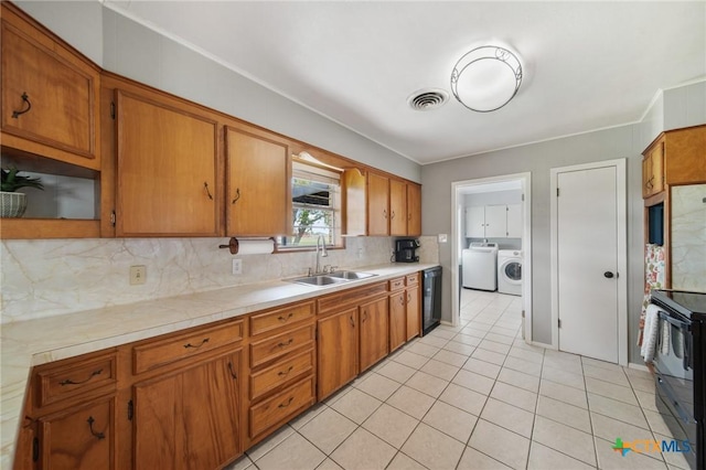 kitchen featuring decorative backsplash, light countertops, separate washer and dryer, a sink, and black appliances
